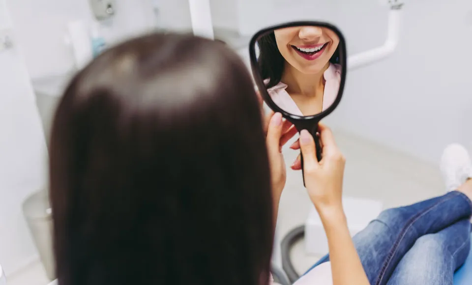 Centro Dental Las Americas patient smiling in the mirror after getting a dental checkup